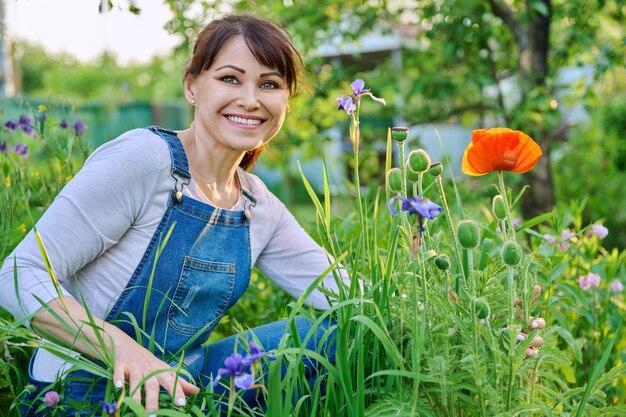 Middle aged woman enjoying the beauty of red poppy