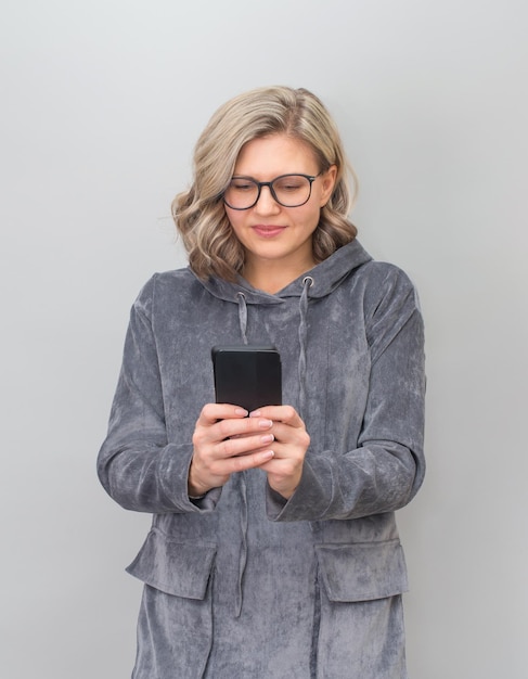 Middle aged woman in eyeglasses texting message on smartphone