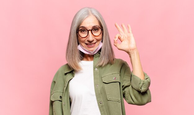 Middle aged woman feeling happy relaxed and satisfied showing approval with okay gesture smiling