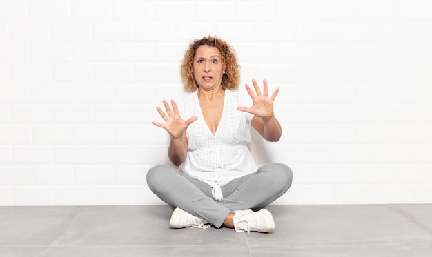 Middle aged woman feeling terrified, backing off and screaming in horror and panic, reacting to a nightmare