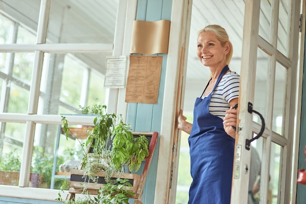 Middle aged woman holding handle on garden house door