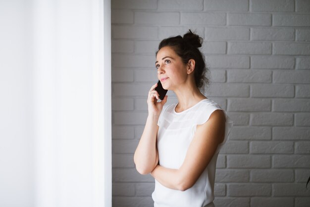 話している携帯電話を保持している中年の女性。