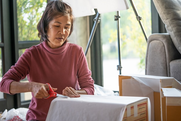 写真 中年女性が商品を梱包してオンラインで顧客に届ける