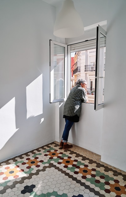 Middle-aged woman leans out of the window in a room with colored hydraulic flooring