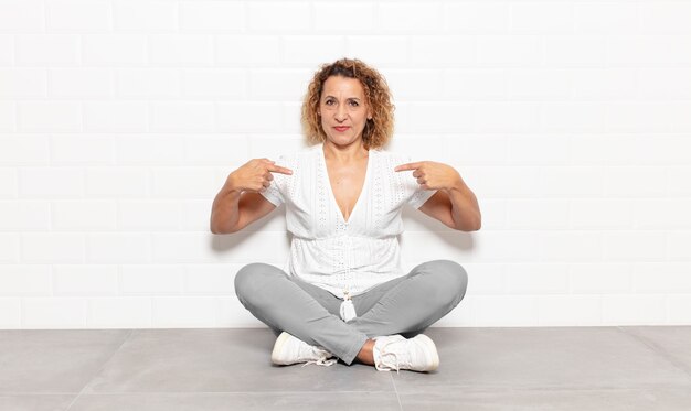 Middle aged woman looking proud, positive and casual pointing to chest with both hands