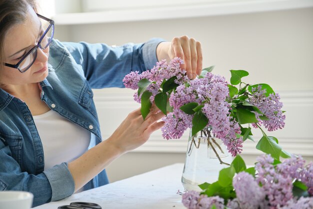 ライラックの枝の花束を作る中年女性