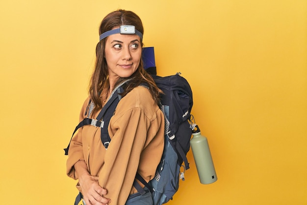 Photo middle aged woman mountaineer gear ready on yellow background
