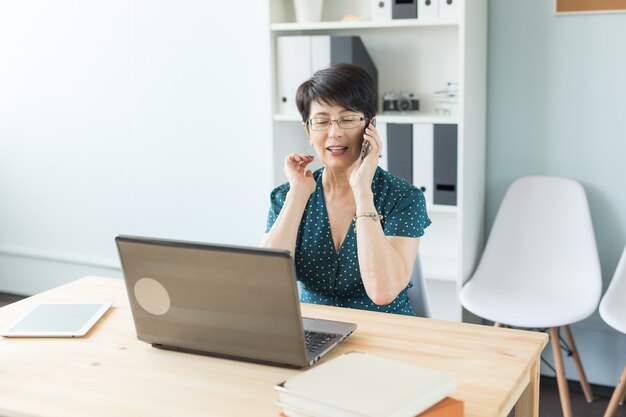 Middle aged woman at office working with laptop and making a