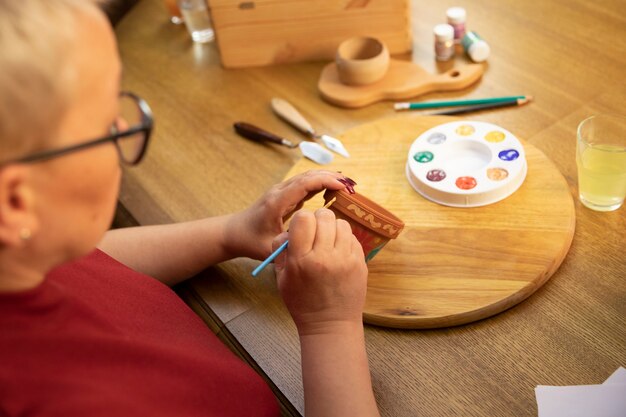 Middle-aged woman paints flower pot in home art studio setting