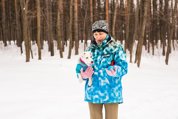 Donna di mezza età che gioca con il suo cane jack russell terrier nel parco innevato