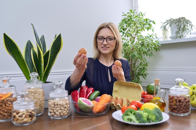 Женщина средних лет профессиональный диетолог сидит за столом с пищевыми яйцами