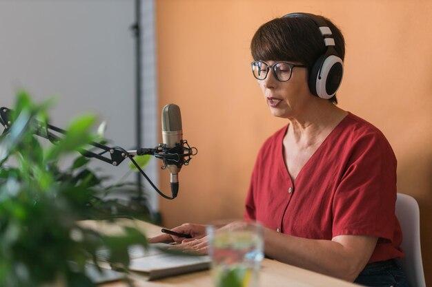 Middle-aged woman radio host making podcast recording for online show - broadcast and dj concept