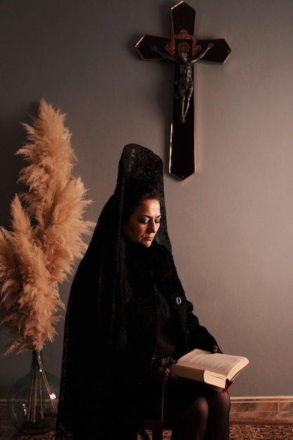 Middle-aged woman reading a bible dressed in a black veil