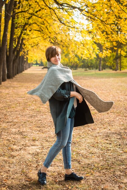 スカーフを着た中年女性が秋の公園を散歩。