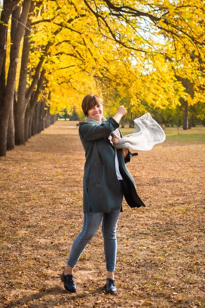 スカーフを着た中年女性が秋の公園を散歩。