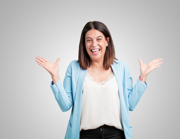 Middle aged woman screaming happy, surprised by an offer or a promotion, gaping, jumping and proud