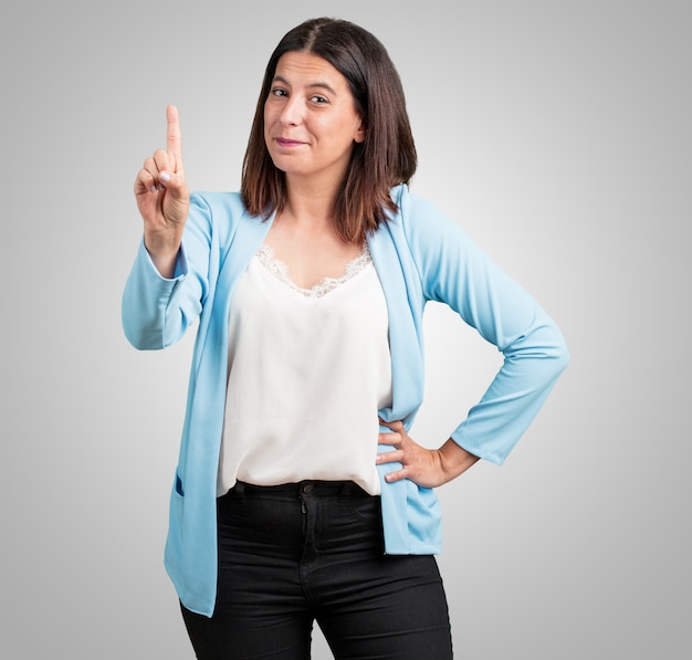 Middle aged woman showing number one, symbol of counting, concept of mathematics, confident and cheerful