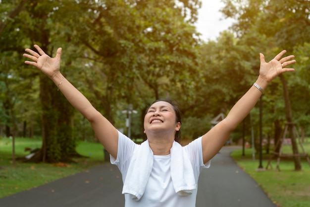 Middle aged woman showing winning and jogging in park.