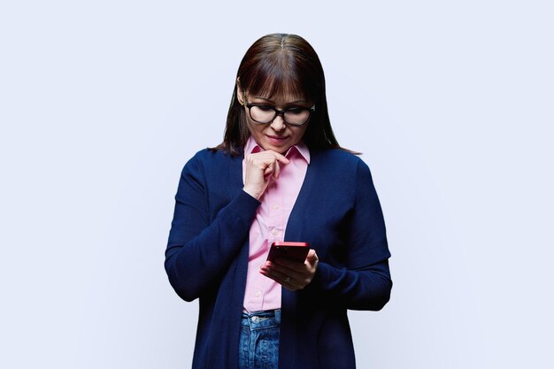 Middle aged woman using smartphone on white background