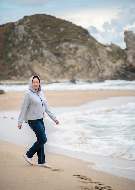中年女性は、秋、冬、アクティブなライフスタイルで海のラインに沿って歩きます。涼しい天候で海に沿って歩く。カリフォルニア海岸