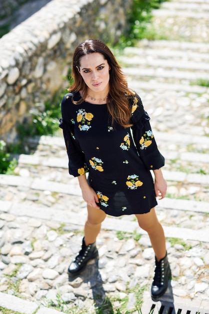 Middle-aged woman wearing flowered dress in urban steps.