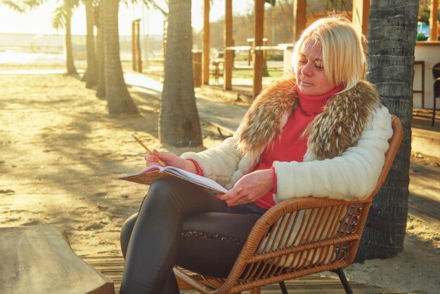 A middle-aged woman with blonde hair sits in a street cafe