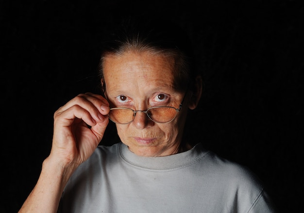 暗い背景のメガネを持つ中年の女性