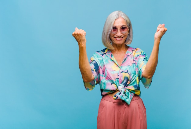 Middle agedd cool woman celebrating an unbelievable success like a winner, looking excited and happy saying take that!