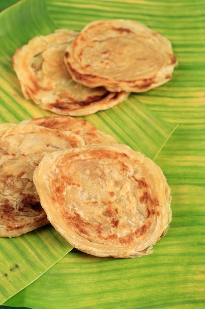 중동 Canai 또는 Paratha Flat Bread, 또는 인도네시아에서는 Roti Maryam이라고도 합니다. 바나나 잎 배경에 고립