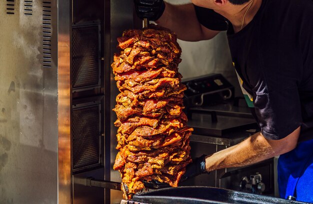 Middle east grilled skewered lamb mutton chef placing meat for\
shawarma or kebab fast food home delivery