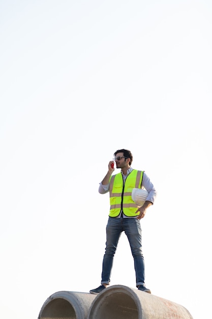 Middle Eastern Civil engineer operate worker on radio to control working at construction site.