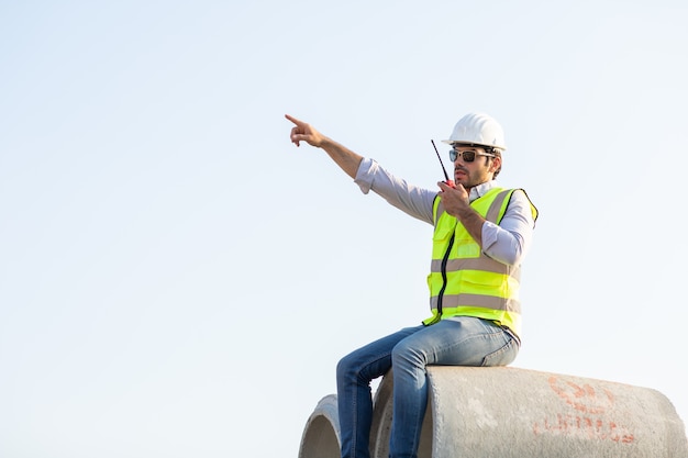 中東の土木技師は、建設現場での作業を制御するために無線で労働者を操作します。