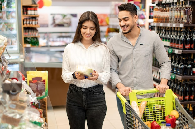 Middle eastern couple buying food doing grocery shopping in supermarket