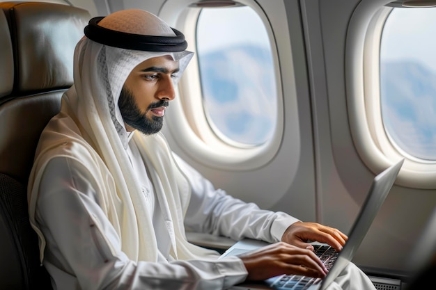 Middle Eastern Entrepreneur in Traditional Attire Productively Working on Laptop While Traveling by Plane