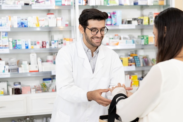 Фото Фармацевт-мужчина с ближнего востока продает лекарства женщине-пациенту по рецепту и дает рекомендации по лекарствам в современной аптеке