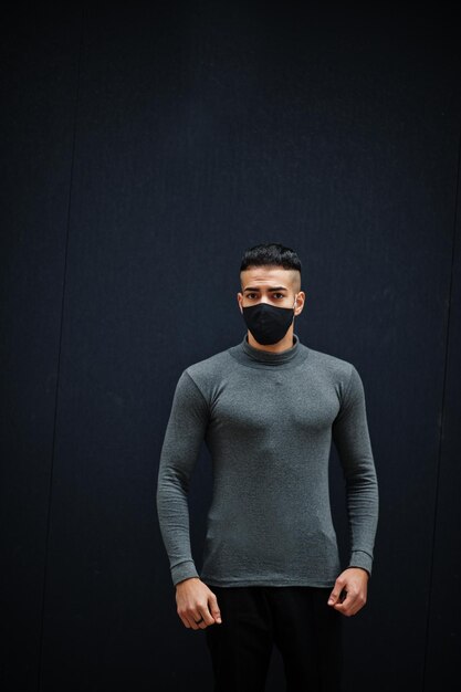 Middle eastern man in gray turtleneck and black face protect mask on isolated background