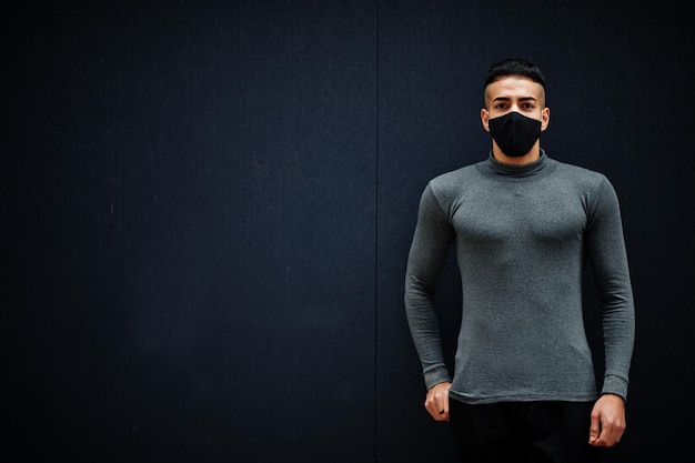 Middle eastern man in gray turtleneck and black face protect mask on isolated background