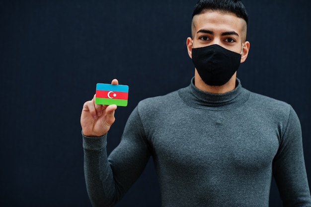 Uomo mediorientale in dolcevita grigio e maschera nera per la protezione del viso