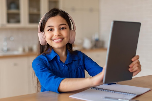 Middle eastern school girl using digital tablet wearing headphones indoor