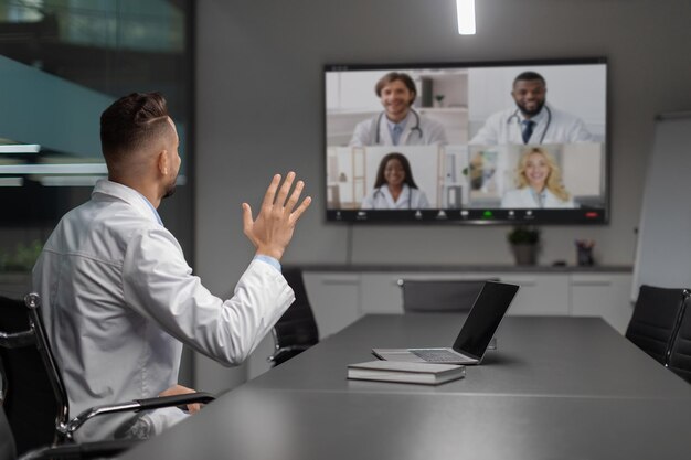 Foto scienziato mediorientale che ha una chat video con colleghi internazionali