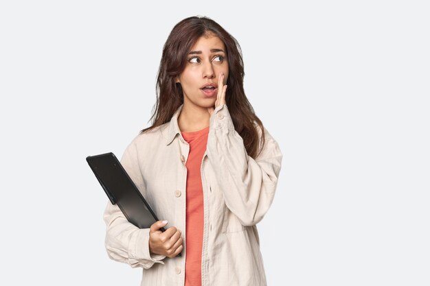 グラフィックタブレットを持った中東の女性が秘密のホットブレーキのニュースを話し,片方に見ています