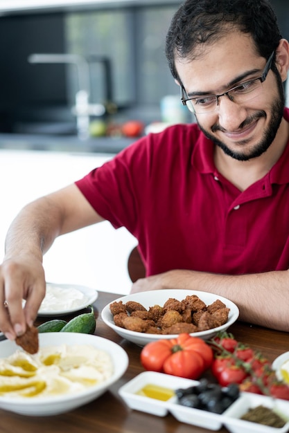 Middle Eastern young man sitting and eating traditional food alone