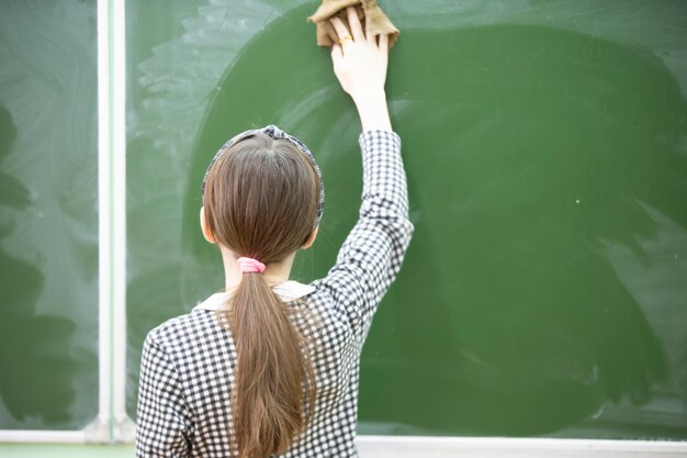 A middle school or junior high school student wipes the blackboard