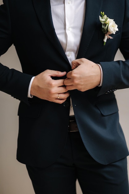 Middle selection of groom fastens the button on his suit Stylish groom