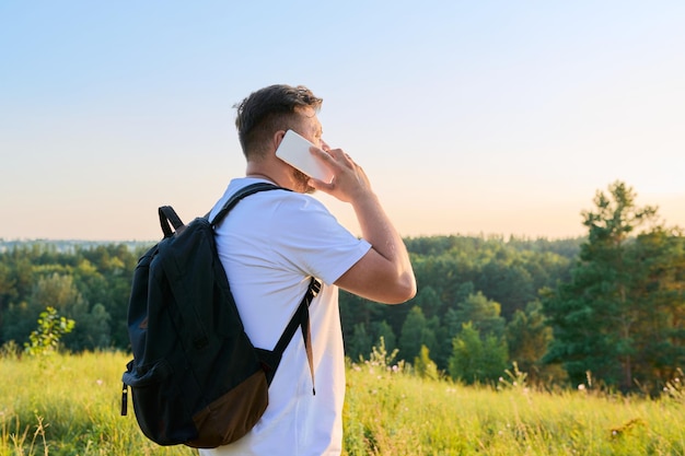 Middleaged bearded man with backpack using smartphone talking on the phone