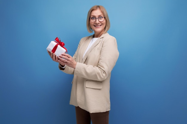 Middleaged business concept s woman in a jacket with a gift on a studio background with copy space