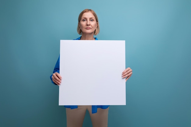 Middleaged business woman holding a poster for notes with a mocap on a blue background copy space