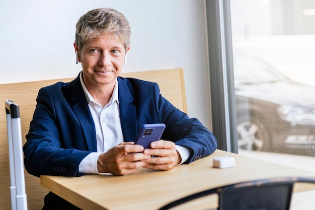 Middleaged businessman dressed in a suit using a telephone with a wireless headset sitting in a bar