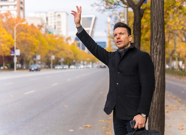 Middleaged caucasian businessman hailing a taxi raising his hand to go to work