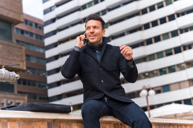Middleaged Caucasian businessman talking on the phone in the city smiling